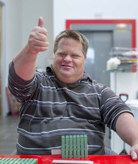 Persona al lavoro in un laboratorio della cooperativa, espressione di inclusione e partecipazione